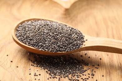 Photo of Spoon with chia seeds on wooden table, closeup