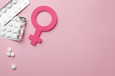 Female gender sign, pills and space for text on pink background, flat lay. Women's health concept