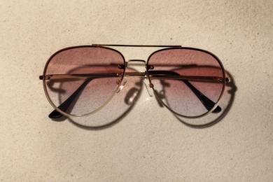 New stylish sunglasses on sand, top view