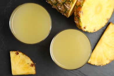 Photo of Delicious pineapple juice and fresh fruit on black table, flat lay