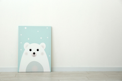 Adorable picture of bear on floor near white wall, space for text. Children's room interior element