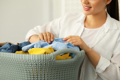 Photo of Woman with basket full of clean laundry indoors, closeup