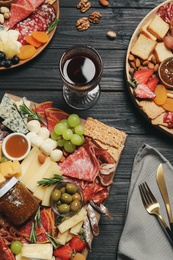 Photo of Assorted appetizers served on black wooden table, flat lay