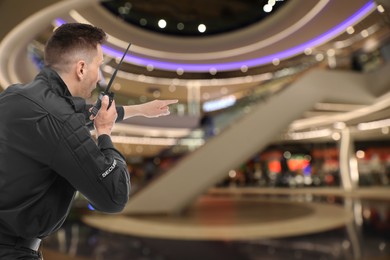 Male security guard using portable radio transmitter in shopping mall