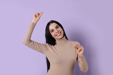 Young woman snapping fingers on violet background