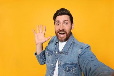 Photo of Funny bearded man taking selfie on orange background
