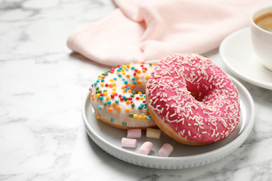 Yummy donuts with sprinkles on white marble table, closeup