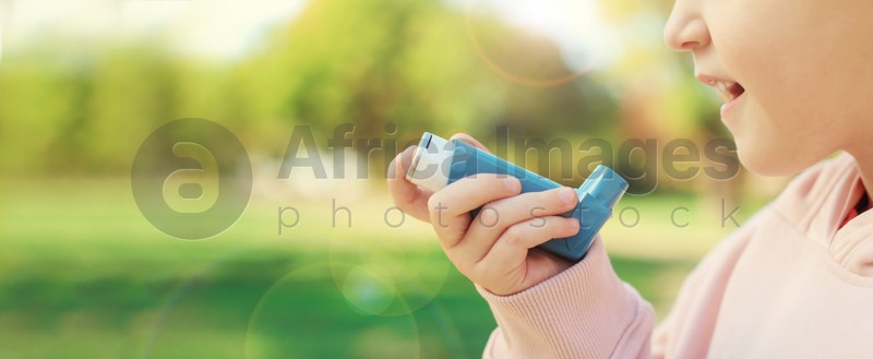 Image of Closeup view of little girl using asthma inhaler outdoors, space for text. Banner design