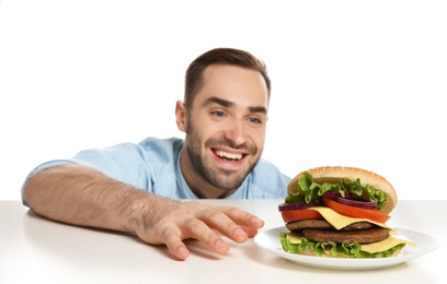 Young hungry man with tasty burger on white background