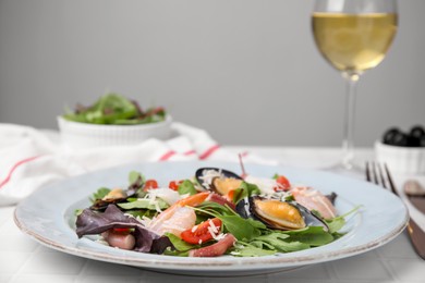 Photo of Plate of delicious salad with seafood on white tiled table