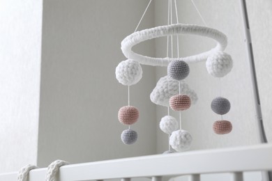Photo of Modern baby mobile under crib near beige wall in room, low angle view