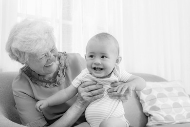 Happy grandmother with little baby at home. Black and white photography