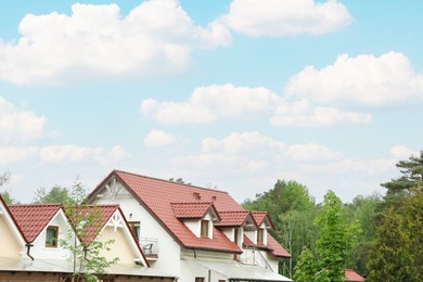 Modern buildings with red roofs near forest on spring day