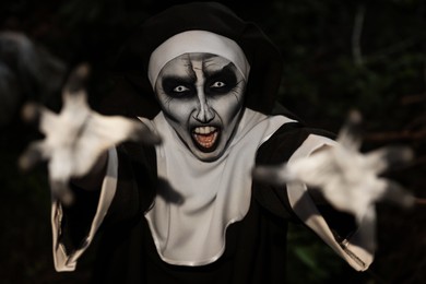 Scary devilish nun frightening outdoors. Halloween party look