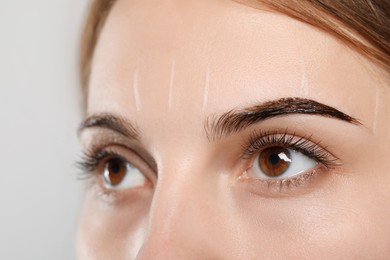 Photo of Woman during eyebrow tinting procedure on grey background, closeup