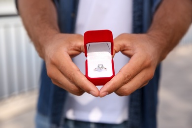 Man with engagement ring outdoors, closeup view