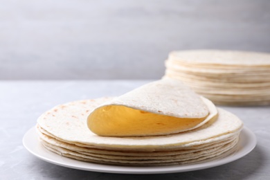 Plate with stack of tasty tortillas on grey table. Space for text