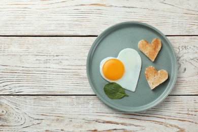 Photo of Romantic breakfast with heart shaped fried egg and toasts on white wooden table, top view. Space for text