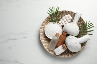 Composition with herbal massage bags and other spa products on white marble table, top view. Space for text