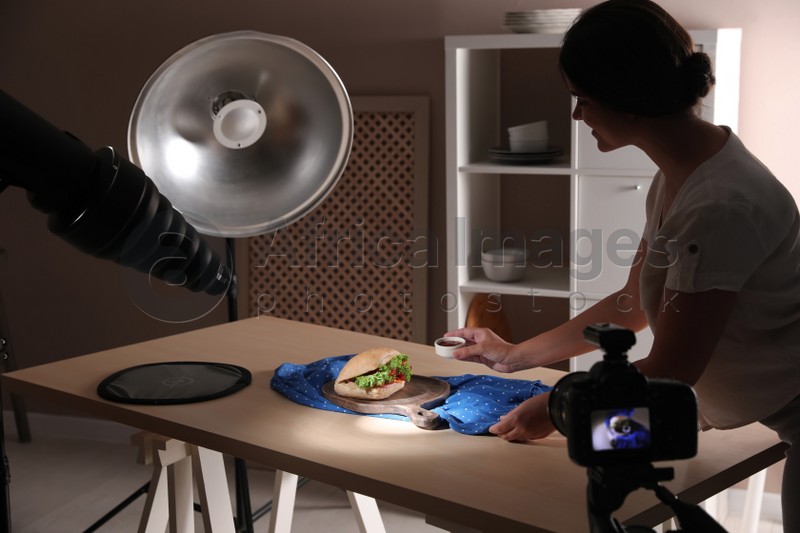 Young woman creating composition with sandwich in studio. Food photography
