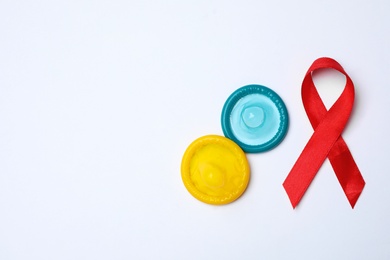Colorful condoms and red ribbon on white background, top view. LGBT concept