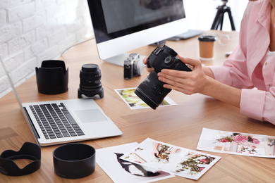 Professional photographer with camera working at table in office, closeup