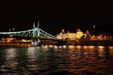 BUDAPEST, HUNGARY - APRIL 27, 2019: Beautiful night cityscape with illuminated Gellert Hotel and Liberty Bridge across Danube river