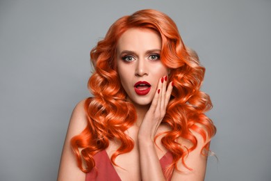 Beautiful woman with long orange hair on light grey background