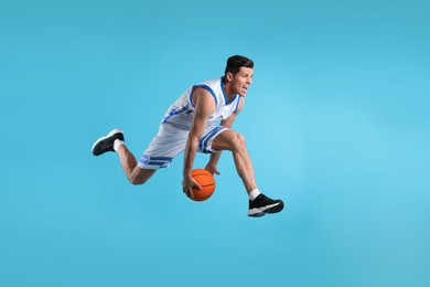 Photo of Professional sportsman playing basketball on light blue background