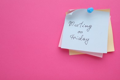 Paper note with words Meeting on Friday pinned to pink background, space for text