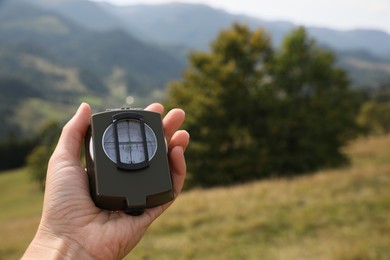 Woman using compass for navigation during journey in mountains, closeup