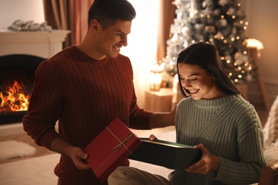 Couple opening gift box in living room with Christmas tree