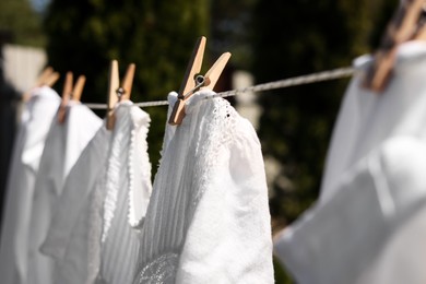 Clean clothes hanging on washing line in garden, closeup. Drying laundry