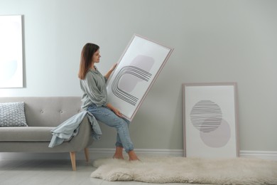 Woman holding picture near wall in room. Interior design