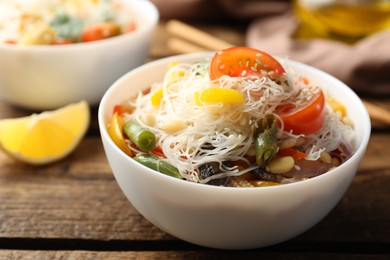 Photo of Tasty cooked rice noodles with vegetables on wooden table