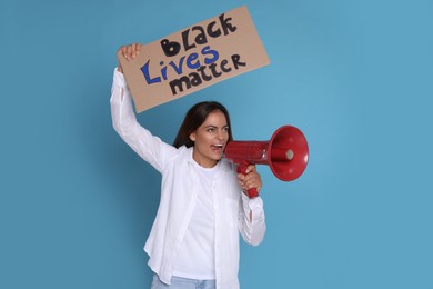 Emotional woman shouting into megaphone while holding sign with phrase Black Lives Matter on light blue background. End Racism