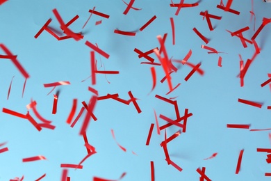 Shiny red confetti falling down on light blue background