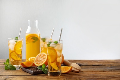 Delicious refreshing drink with orange slices on wooden table. Space for text