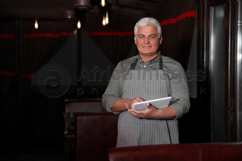 Senior business owner with tablet in his restaurant