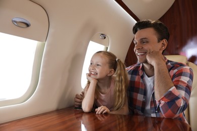 Father with daughter looking out window in airplane during flight