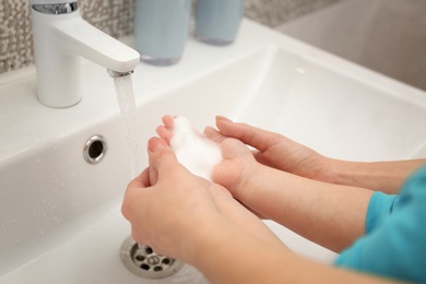 Mother and daughter washing hands in bathroom at home, closeup