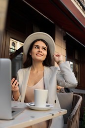 Photo of Beautiful young woman using smartphone in outdoor cafe
