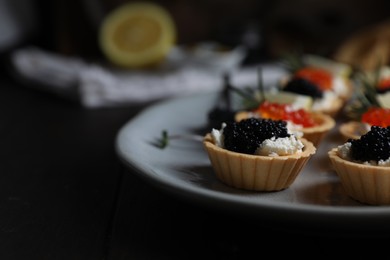 Photo of Delicious tartlets with red and black caviar served on table, closeup. Space for text