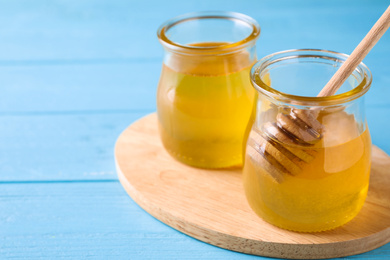 Tasty aromatic honey on light blue wooden table