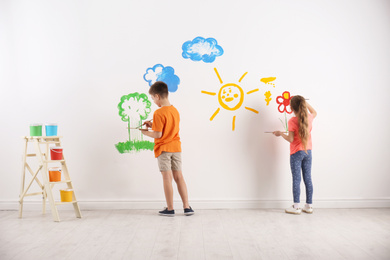 Photo of Little children painting on white wall indoors