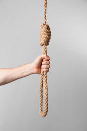 Man holding rope noose on light background, closeup