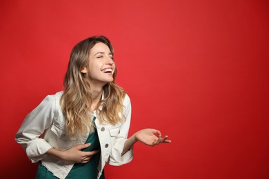 Cheerful young woman laughing on red background. Space for text