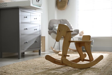 Cute wooden rocking horse in baby room interior