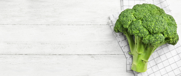 Top view of fresh green broccoli on white wooden table, space for text. Banner design 