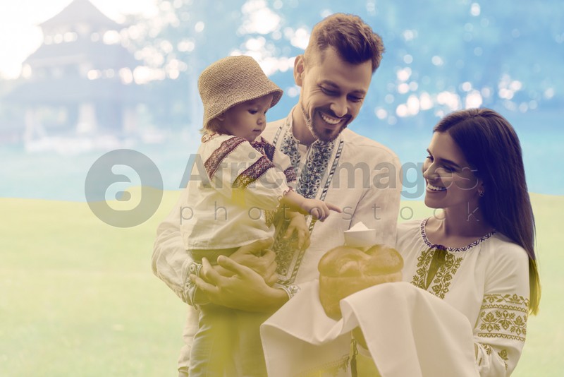 Double exposure of happy family wearing national clothes with bread and salt and Ukrainian flag